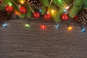 Fototapeta na wymiar Christmas decorations with branches of fir tree, christmas lights, ball and Pine cones on wooden background. copy space