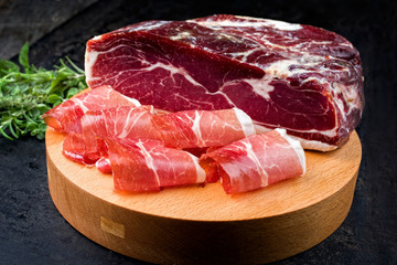 Traditional dry cured and smoked ham with a bouquet garni offered as closeup on a modern design...