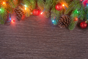 Christmas decorations with branches of fir tree, christmas lights, ball and Pine cones on wooden background. copy space