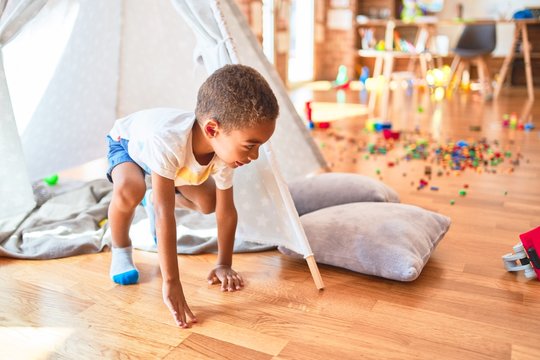 Beautiful african american toddler playing inside tipi smiling at kindergarten