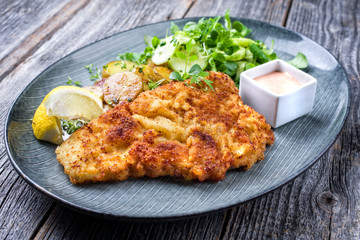Deep fried Wiener schnitzel from veal topside with fried potatoes and lettuce as closeup modern...