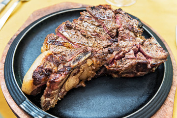Black round plate with cut grilled T-bone steak
