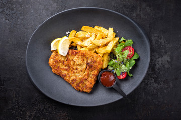 Frittiertes Wiener Schnitzel vom Kalb von der Oberschale angeboten mit Pommes Frites und Salat als...