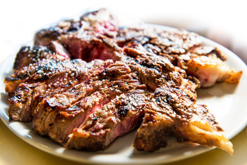 White round plate with cut grilled T-bone steak