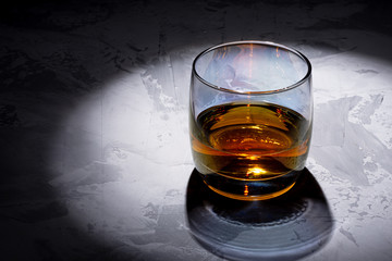Glass of whiskey with ice on a black background. Concrete background. Marble countertop. Concrete worktop. Whiskey / Brandy / Cognac / Rum. Glass with a strong drink.