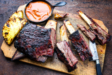 Barbecue smoked sliced hot marinade chuck beef ribs with pineapple and spicy chili sauce as top view sliced on a wooden cutting board
