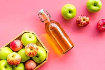 Apple cider in bottle near tray with fruits on pink background top view copy space