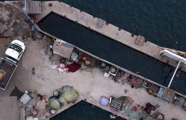 View from above of pier. A car is parked on the pier. Fishing gear scattered across the pier