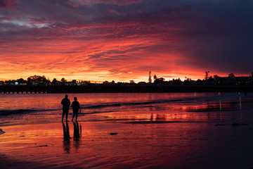 Red beautiful sunset Santa Cruz couple walking along the ocean silhouette