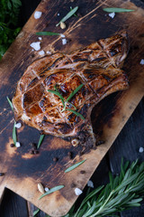 a large piece of fried meat on a cutting board, spices and aromatic herbs.