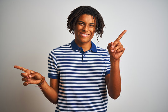 Afro man with dreadlocks wearing striped blue polo standing over isolated white background smiling confident pointing with fingers to different directions. Copy space for advertisement