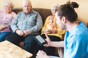 Nurse reading to senior men and women from a story in an e-book