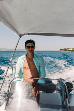 Man in sunglasses driving and navigating yacht in the sea. Sailing man on yacht in ocean