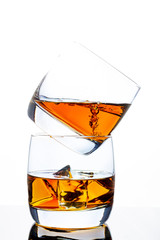 Two glasses of whiskey with ice. A pyramid of glasses. White background. Whiskey / Brandy / Cognac / Rum. Glass with a strong drink.