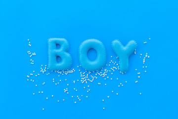 Boy word as decoration for baby shower on blue background top view