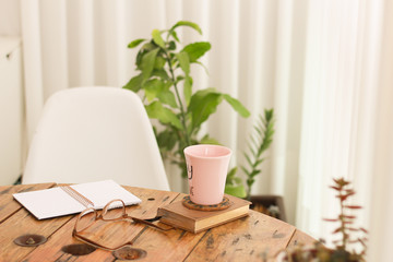 open notebook on home wooden table with coffee mug and plants
