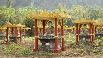 Fototapeta na wymiar Buddha Statues in a green field at the base of Mount Zwegabin near Hpa-An, Myanmar.