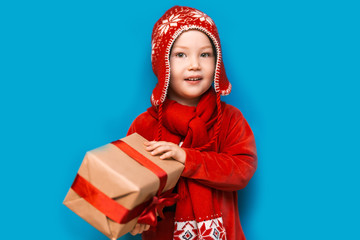 Christmas time. boy with Santa Claus Hat holding christmas gift with red tape and wery surprised face with open mouth