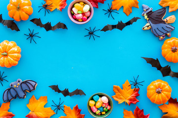 Bright Halloween composition with sweets, bats and pumpkins on blue background top view frame space for text