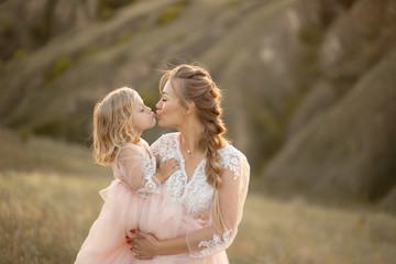 Mom with daughter in pink fairy-tale dresses walk in nature. Little princess childhood