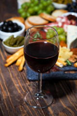 glass of red wine and a platter of delicious cheeses, fruits and meats