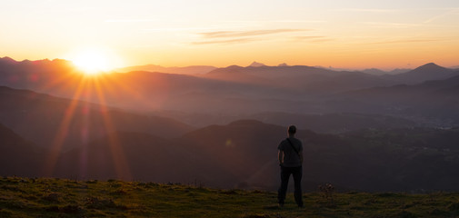 Fototapeta na wymiar Hiker and sun at sunset over the mountains of Gipuzkoa