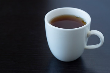 Tea in a white cup and a white teapot on a dark background