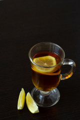 Tea with lemon in a glass cup on a dark background