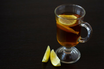 Tea with lemon in a glass cup on a dark background