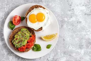 Avicado toast. Egg sandwich appetizer. Top view of balanced brunch food with rye bread. Healthy vegetarian dish recipe with tomato, basil and chili. Gourmet snack. Fitness vegan burger. Copy space