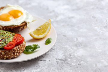 Avocado meal. Healthy egg toast on rye bread with tomato. Vegetarian brunch dish. Delicious green burger recipe for breakfast. Snack with tomatoes and basil. Organic fitness lunch food. Copy Space