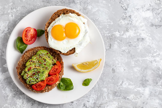 Avicado toast. Egg sandwich appetizer. Top view of balanced brunch food with rye bread. Healthy vegetarian dish recipe with tomato, basil and chili. Gourmet snack. Fitness vegan burger. Copy space