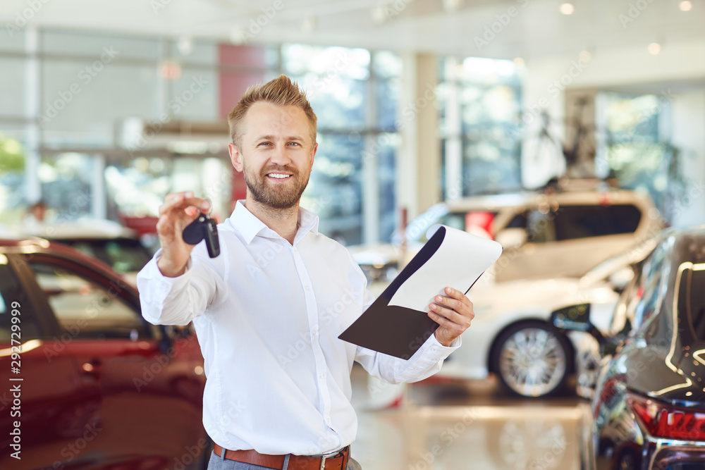 Wall mural A car dealer smiling standing in a showroom.