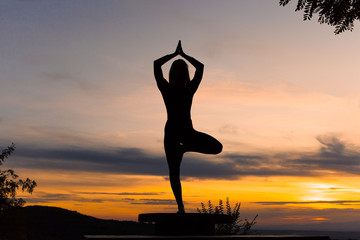 Silhouette woman coach yoga practice at sunset. Vrikshasana. Tree Pose
