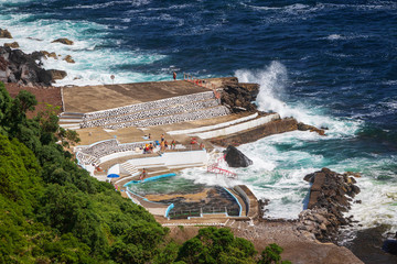 People by a seawater swimming pool Foz da Ribeira do Guilherme, Sao Miguel island, Azores