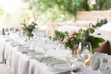 Wedding table setting decorated with fresh flowers in a brass vase. Wedding floristry. Banquet...