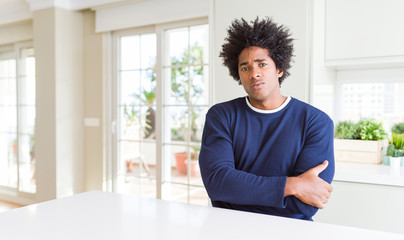 Young african american man wearing casual sweater sitting at home skeptic and nervous, disapproving expression on face with crossed arms. Negative person.