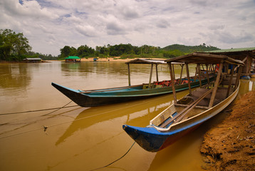 Naklejka na ściany i meble Colored wooden boats to transport passengers, moored in the jungle river of Taman Negara, Malaysia.
