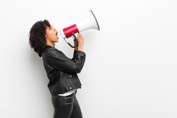young pretty black woman with a megaphone wearing a leather jacket against white wall
