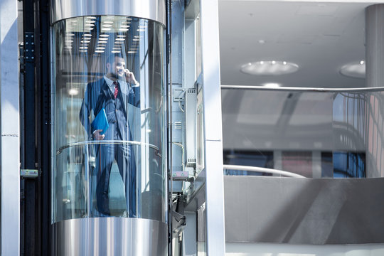 Businessman in elevator talking by phone