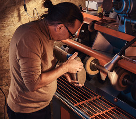 Experienced pensive person is making custom made shoes at his personal workshop.