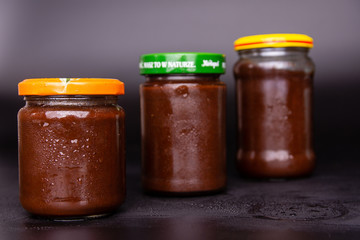 three jars of plum jam on a black background