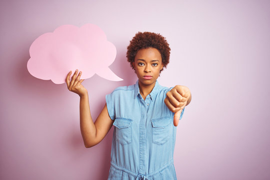Young african american woman holding speech bubble over pink isolated background with angry face, negative sign showing dislike with thumbs down, rejection concept
