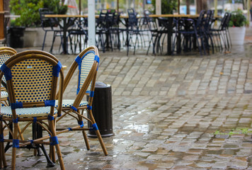 Chairs and tables on the street, cafe. It's raining in the city
