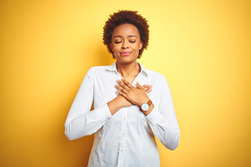 African american business woman over isolated yellow background smiling with hands on chest with...