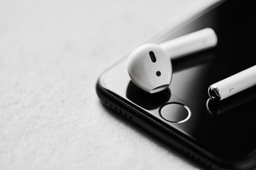 White wireless bluetooth earphones or headphones on smartphone over concrete background. Close up....