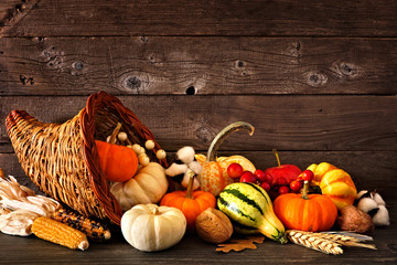 Thanksgiving cornucopia filled with autumn pumpkins and vegetables against a rustic dark wood background - Powered by Adobe