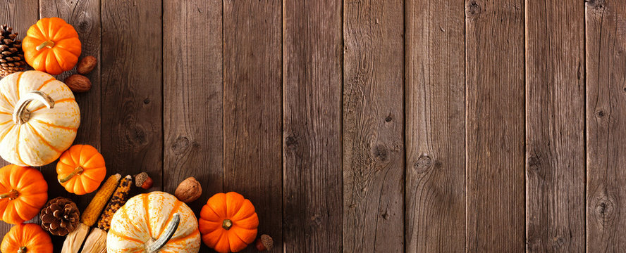 Autumn corner border banner of pumpkins and fall decor on a rustic wood background with copy space