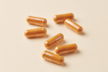 Turmeric capsules. Bright paper background. Close up. 