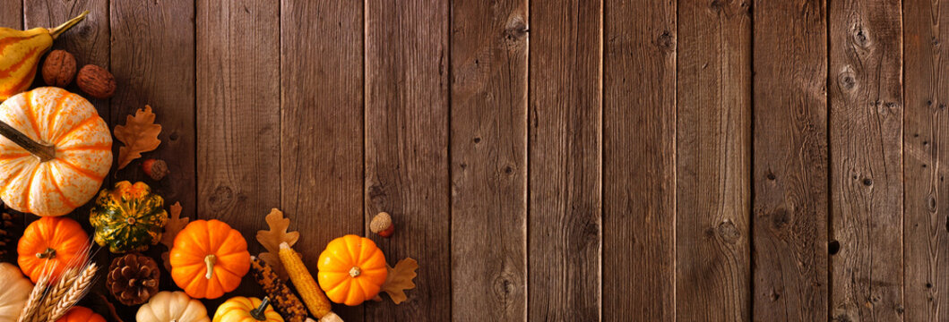 Autumn corner border banner of pumpkins, gourds and fall decor on a rustic wood background with copy space
